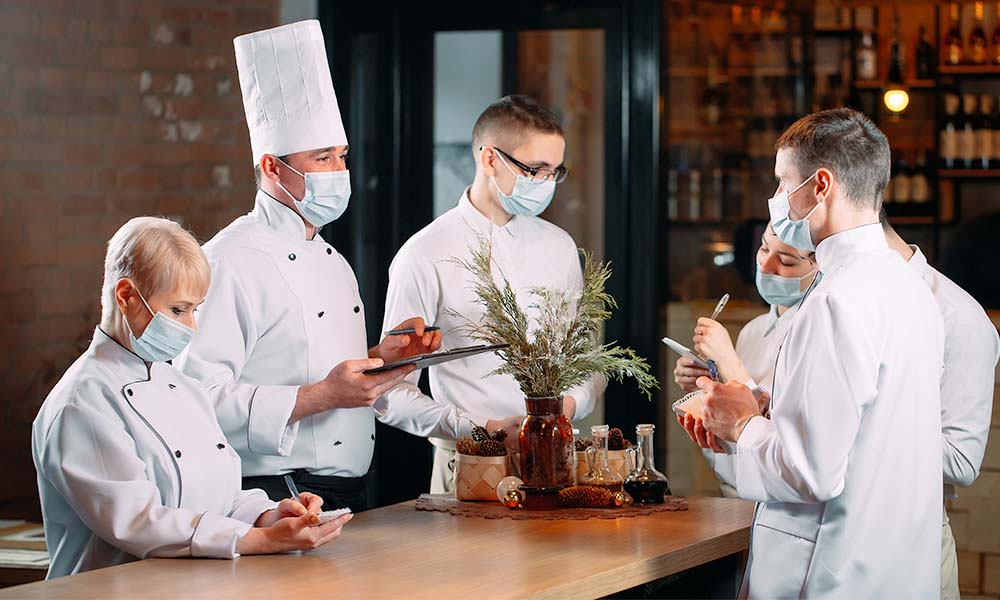Chef having meeting with kitchen staff at restaurant