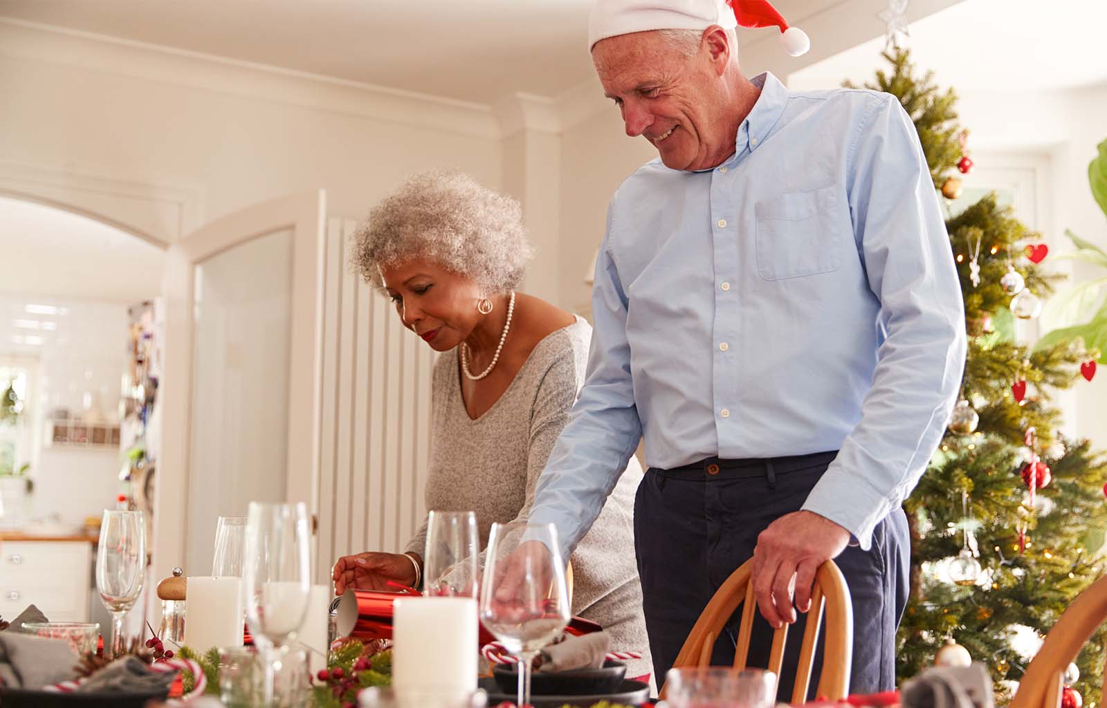 Elderly couple setting up dinner table at Christmas
