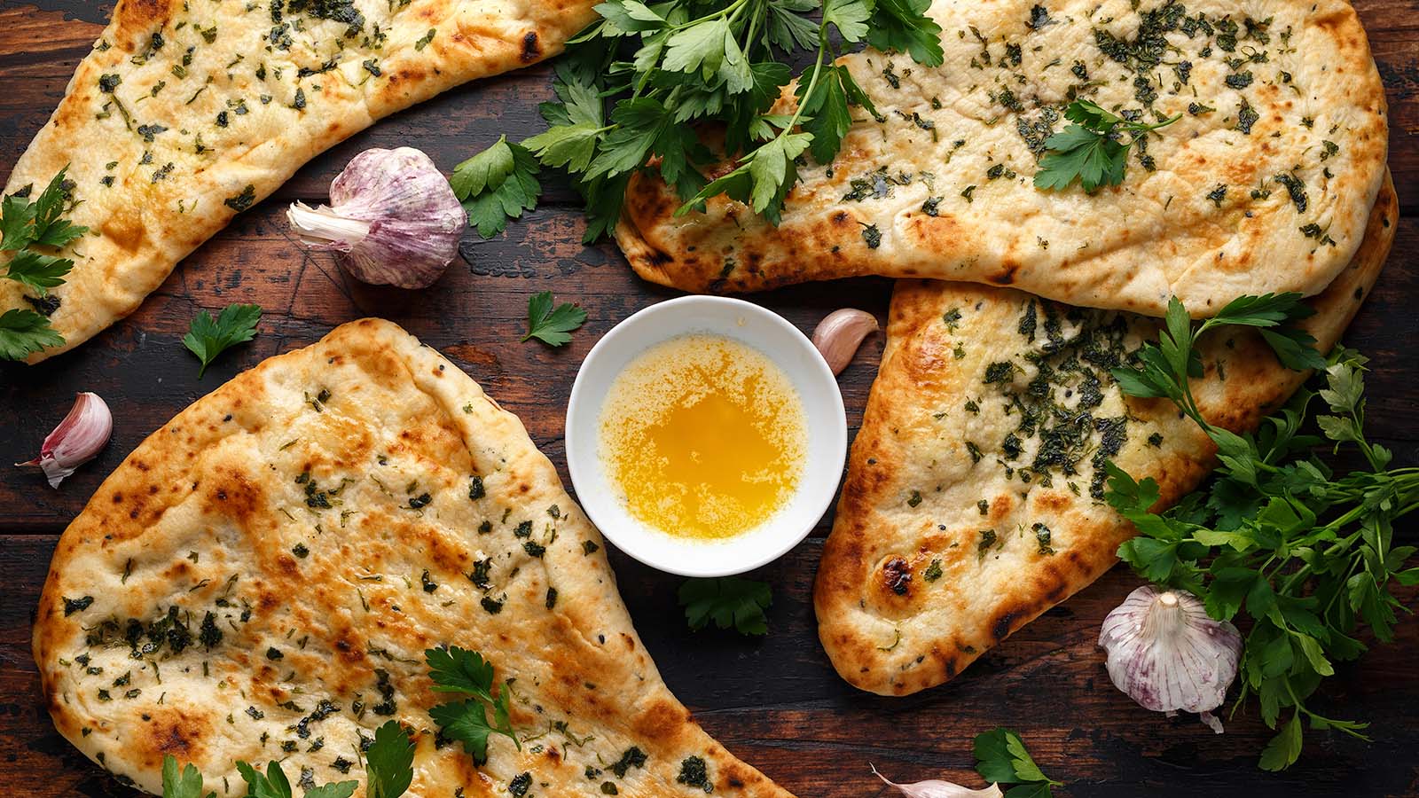 Indian naan bread with garlic butter on wooden table