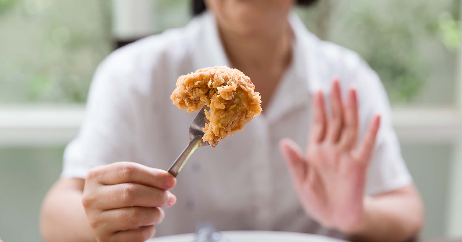 woman in white shirt holding up a piece of fried batter