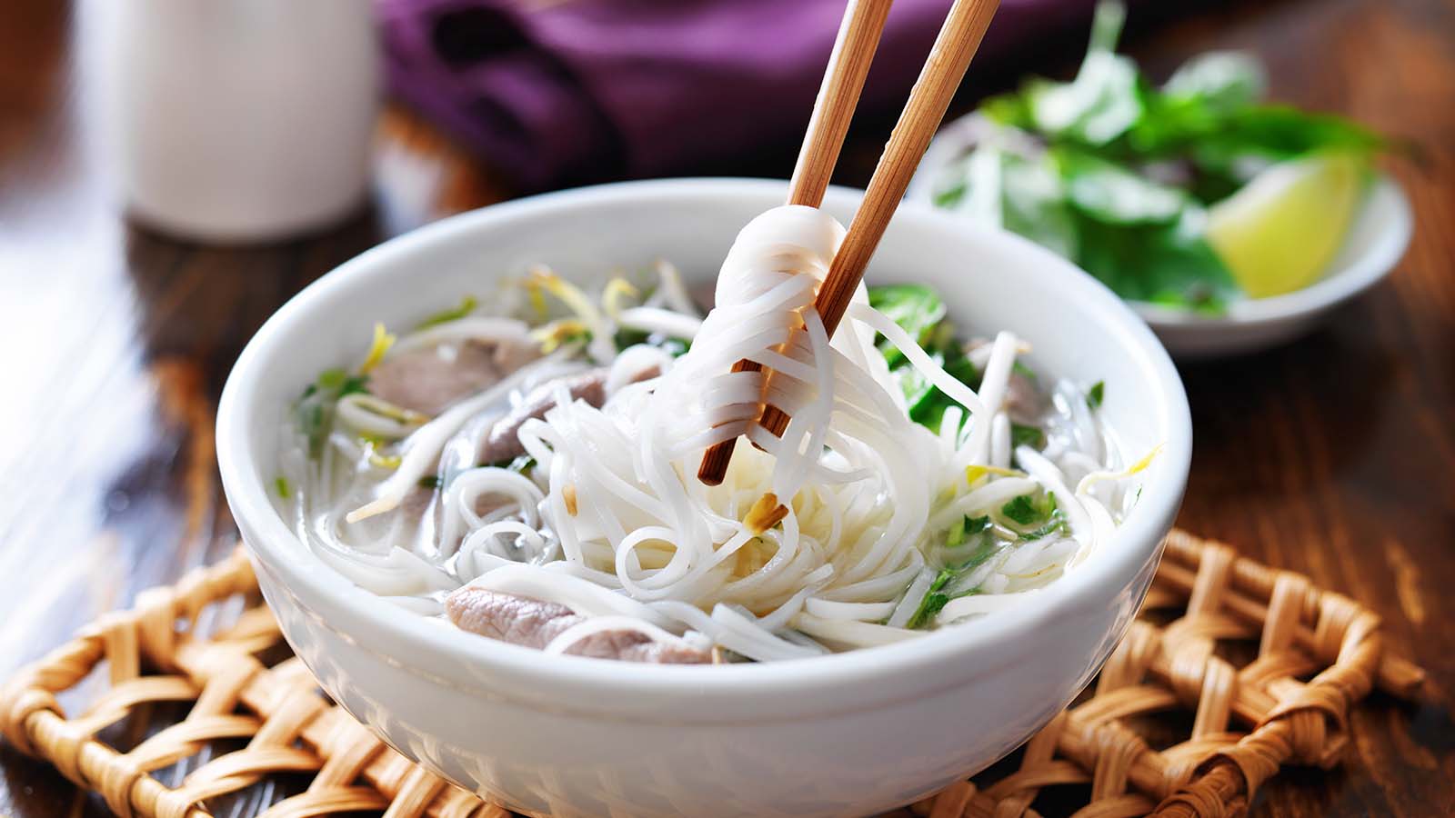 Noodles in white bowl on whicker coaster