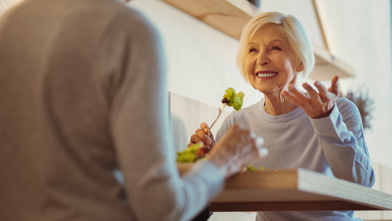Senior woman smiling while eating and talking