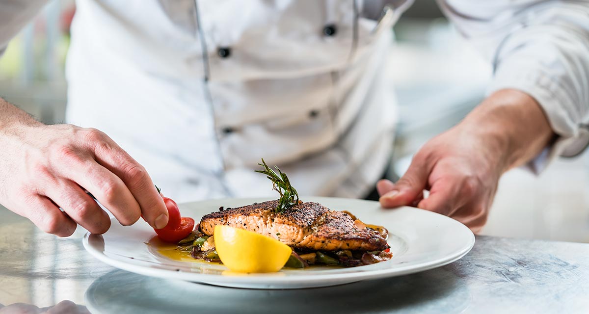 Chef finishing plate with salmon