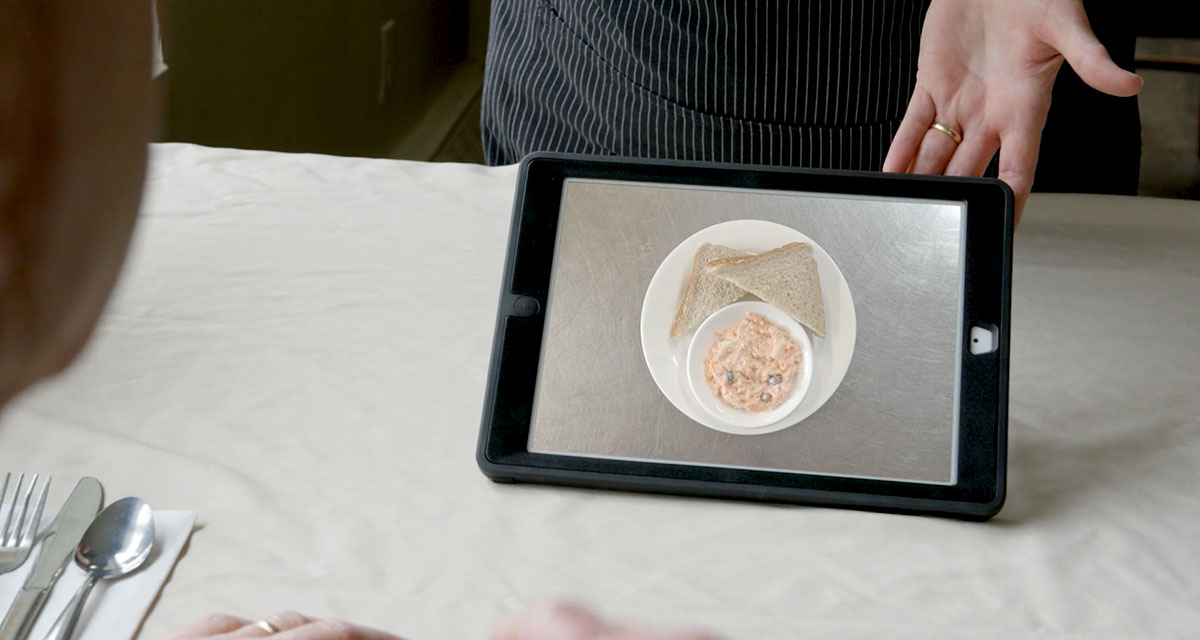 Facility care worker showing longterm care resident food options on a tablet using MealSuite<sup>®</sup> Touch