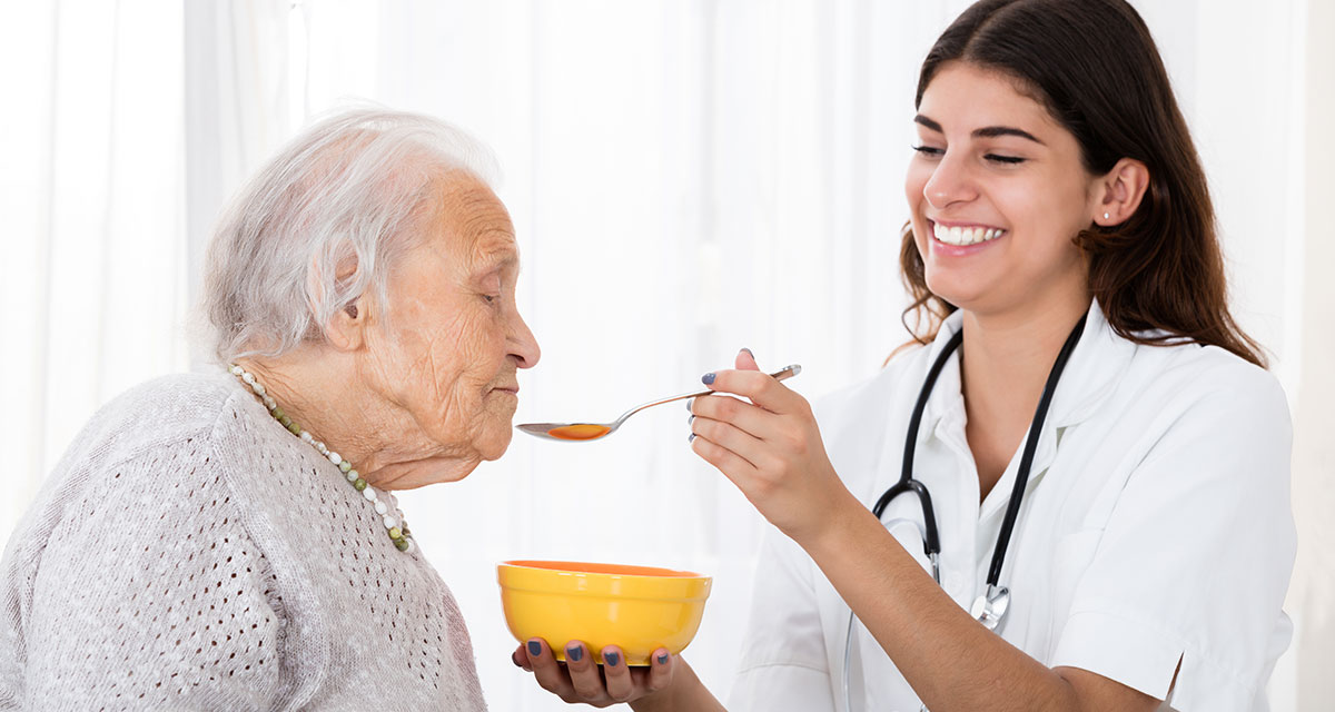 Longterm Care Worker feeding resident a bowl of soup