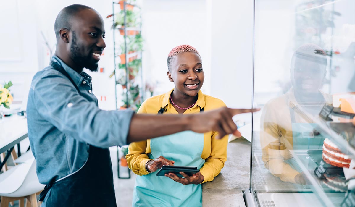 African Amercian man in blue shirt and African American woman in yellow working in cafe