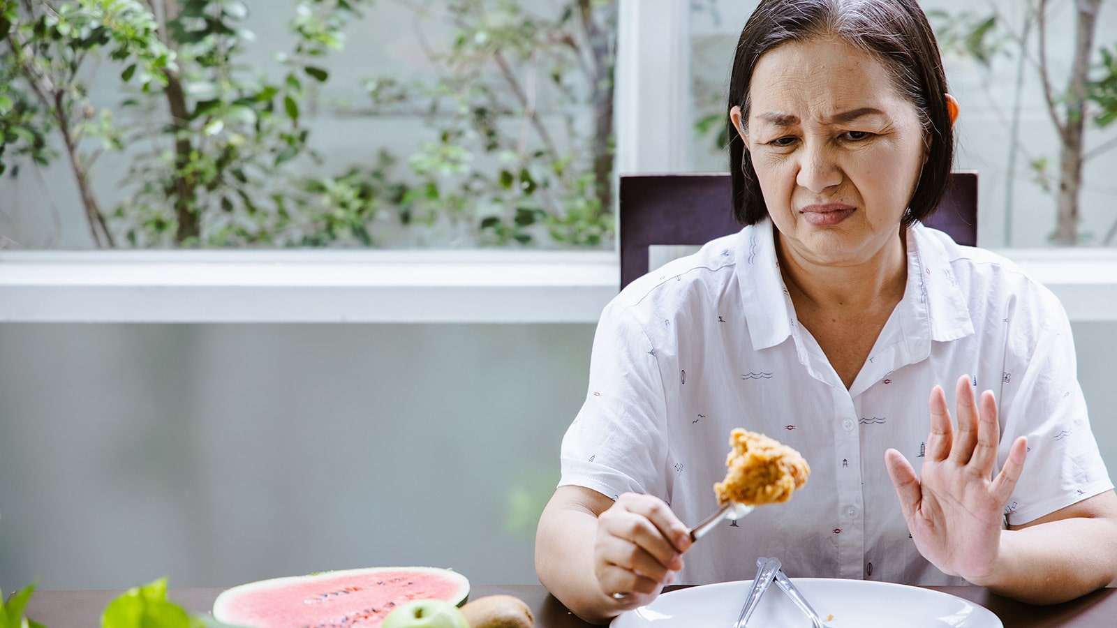 Asian woman in white shirt showing disklike of food on fork
