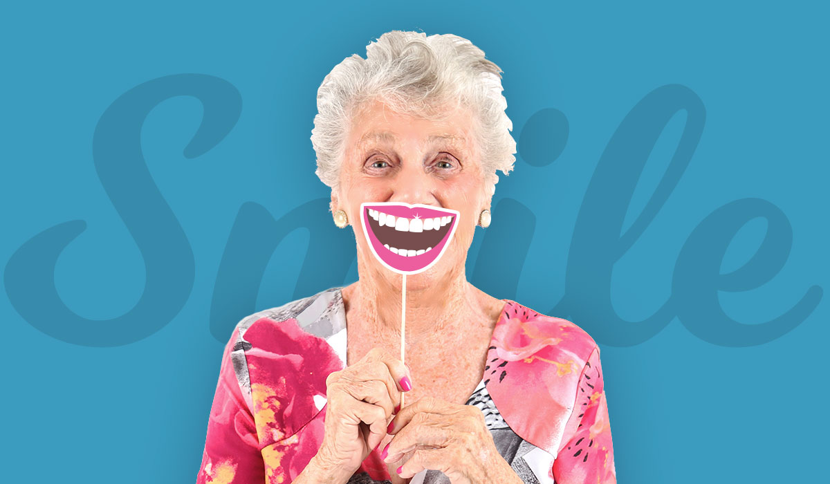 Senior woman in floral blouse holding up a smile prop