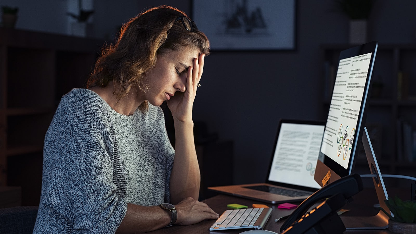 Woman with hand on head at desk stressed out