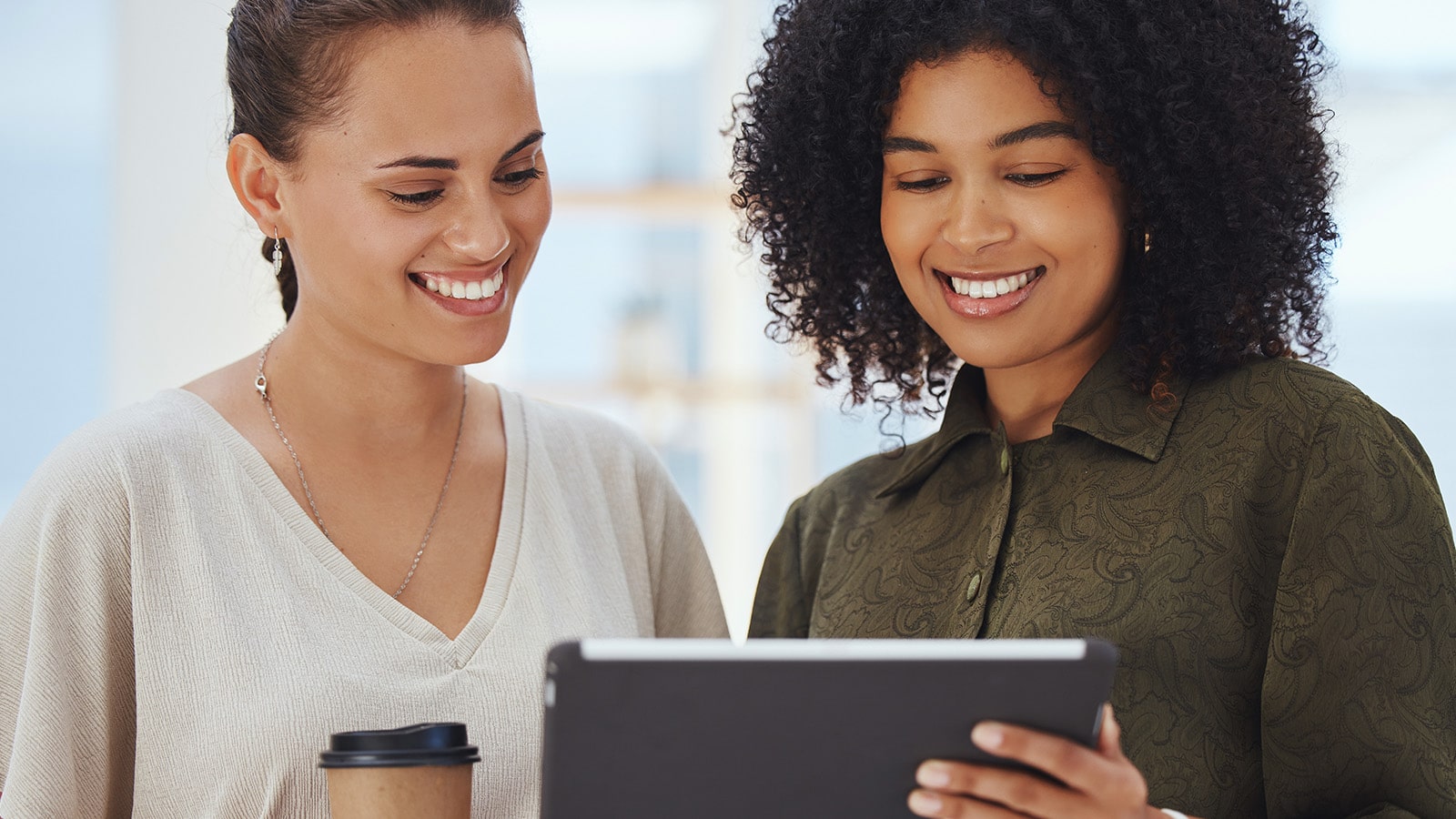 African american women smiling as they look at tablet