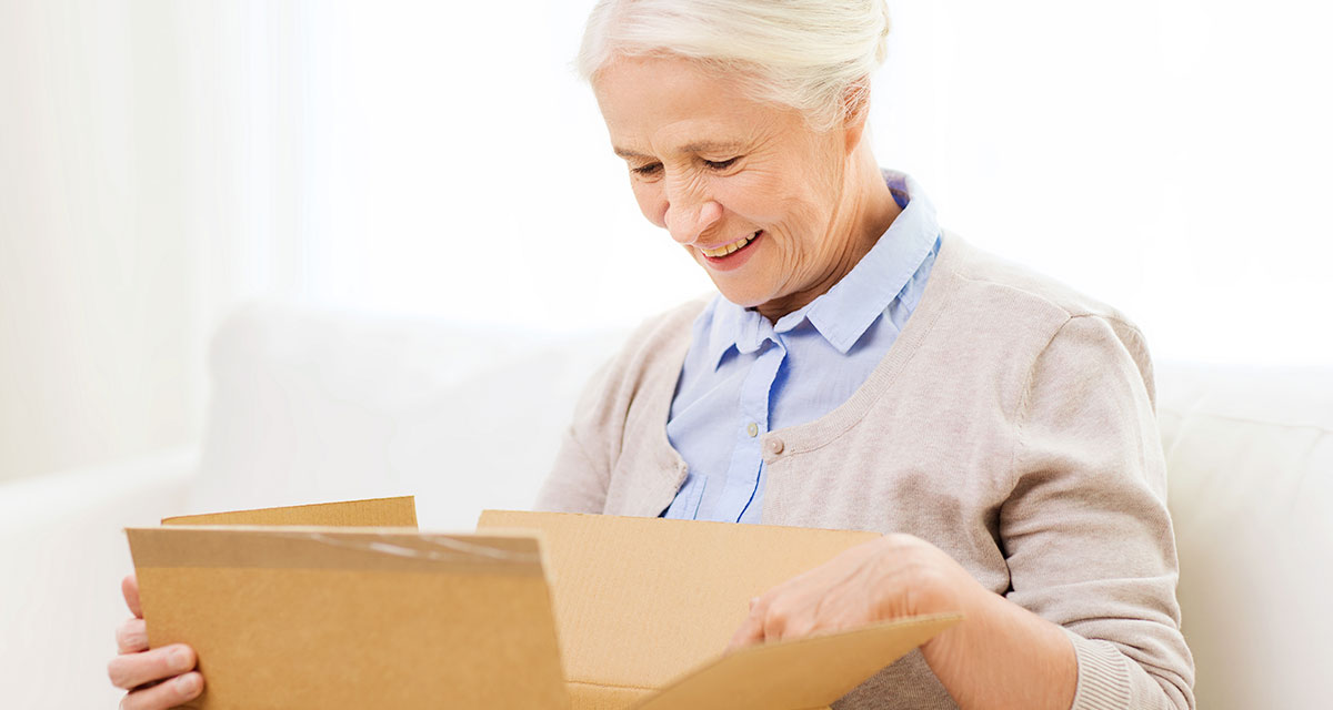 Woman opening box Femail senior citizen opening cardboard box