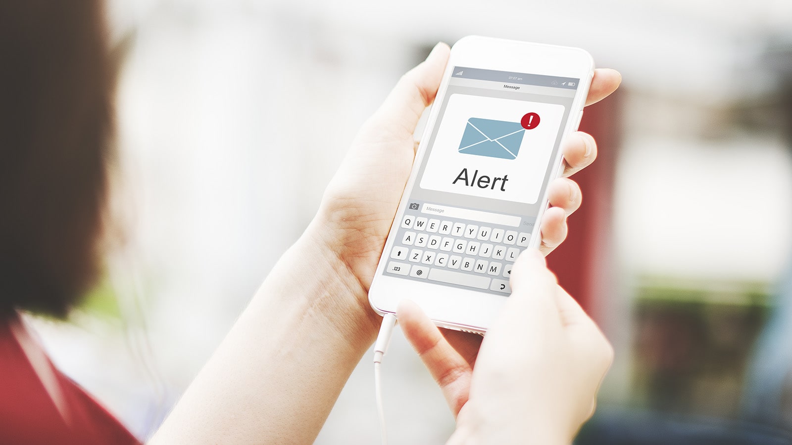 Woman holding white cell phone with an alert message