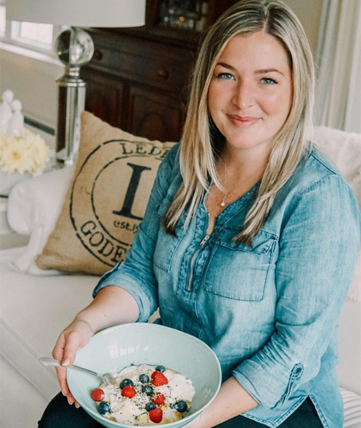 Woman wearing blue sitting holding a bowl of food