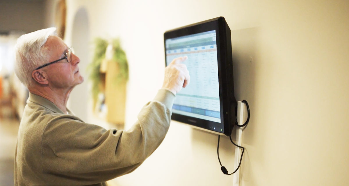 elderly man tapping on a touchscreen