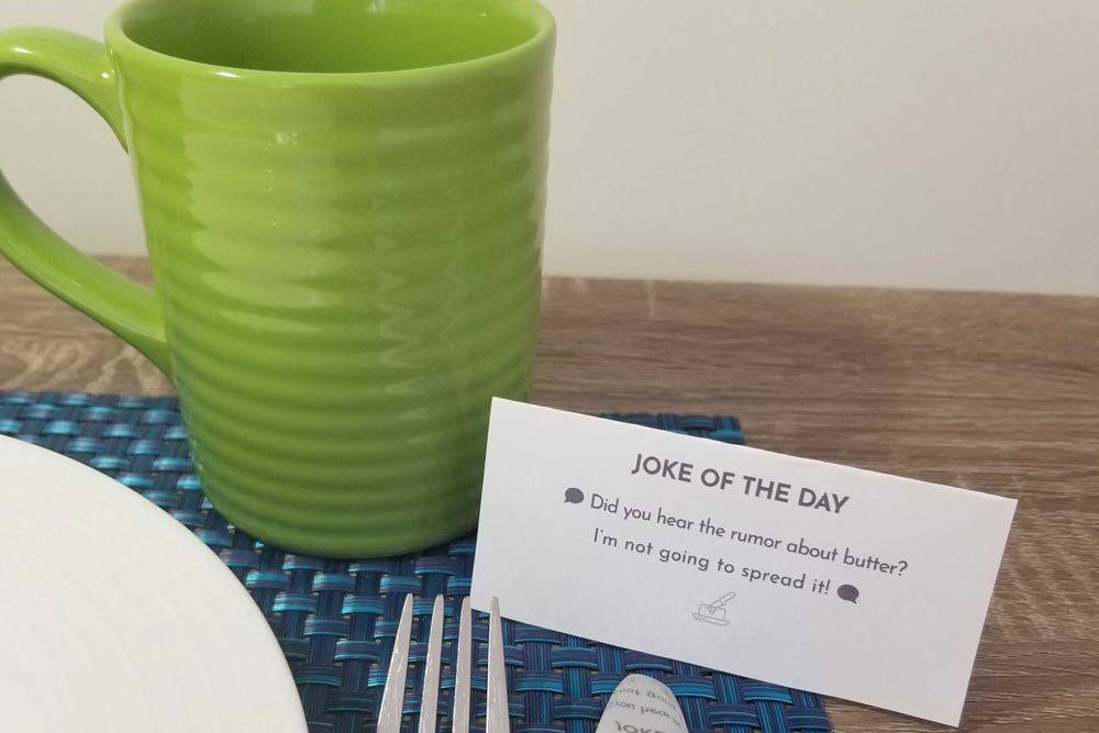 Joke card placed beside green mug on blue placemat