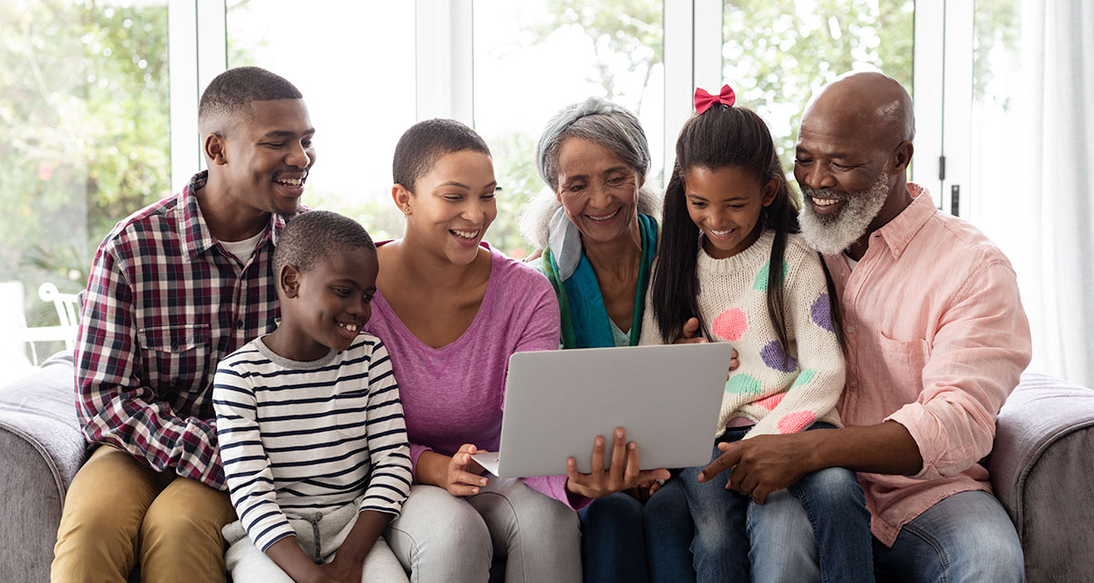 African american family sitting on couch looking at laptop