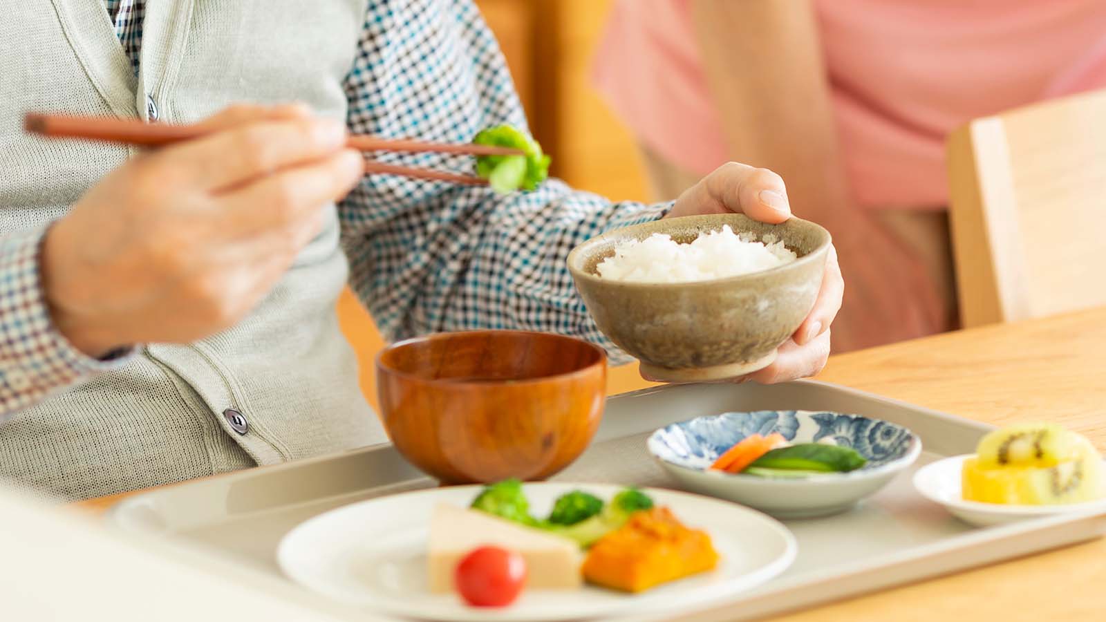 Man with chop sticks eating rice and vegetables from bowl