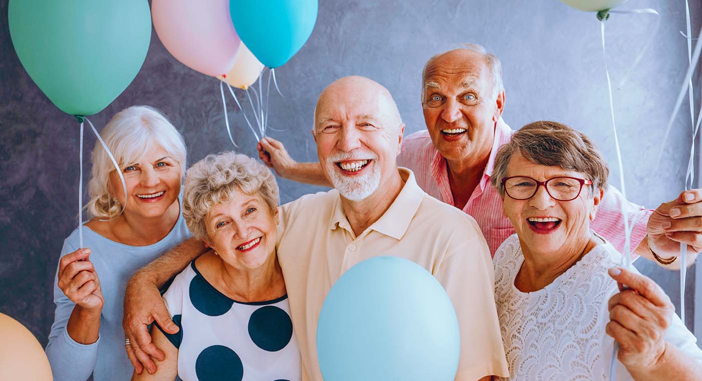 group of seniors holding balloons while smiling